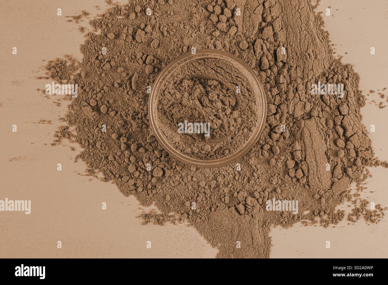 Un pot ouvert de poudre lâche dans un ton de bronze pour la peau foncée sur un fond de beaucoup de texture lâche. Le concept de cosmétiques décoratifs Banque D'Images