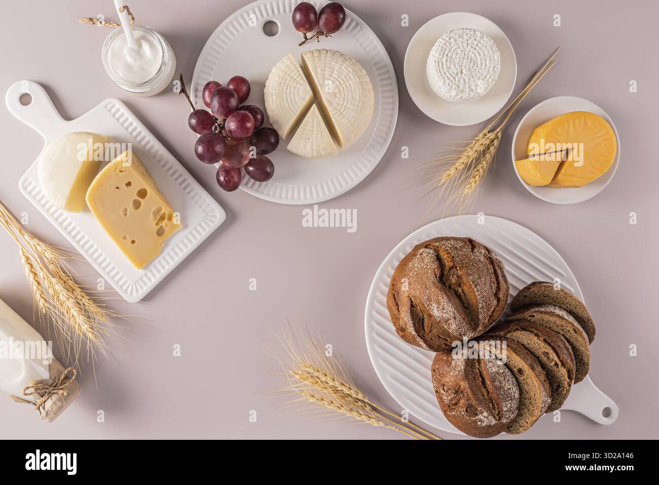Gâteries laitières traditionnelles pour les vacances de Shavuot. fromage, fromage cottage, crème sure, pain, raisins sur plateaux en céramique blanche sur fond pastel Banque D'Images
