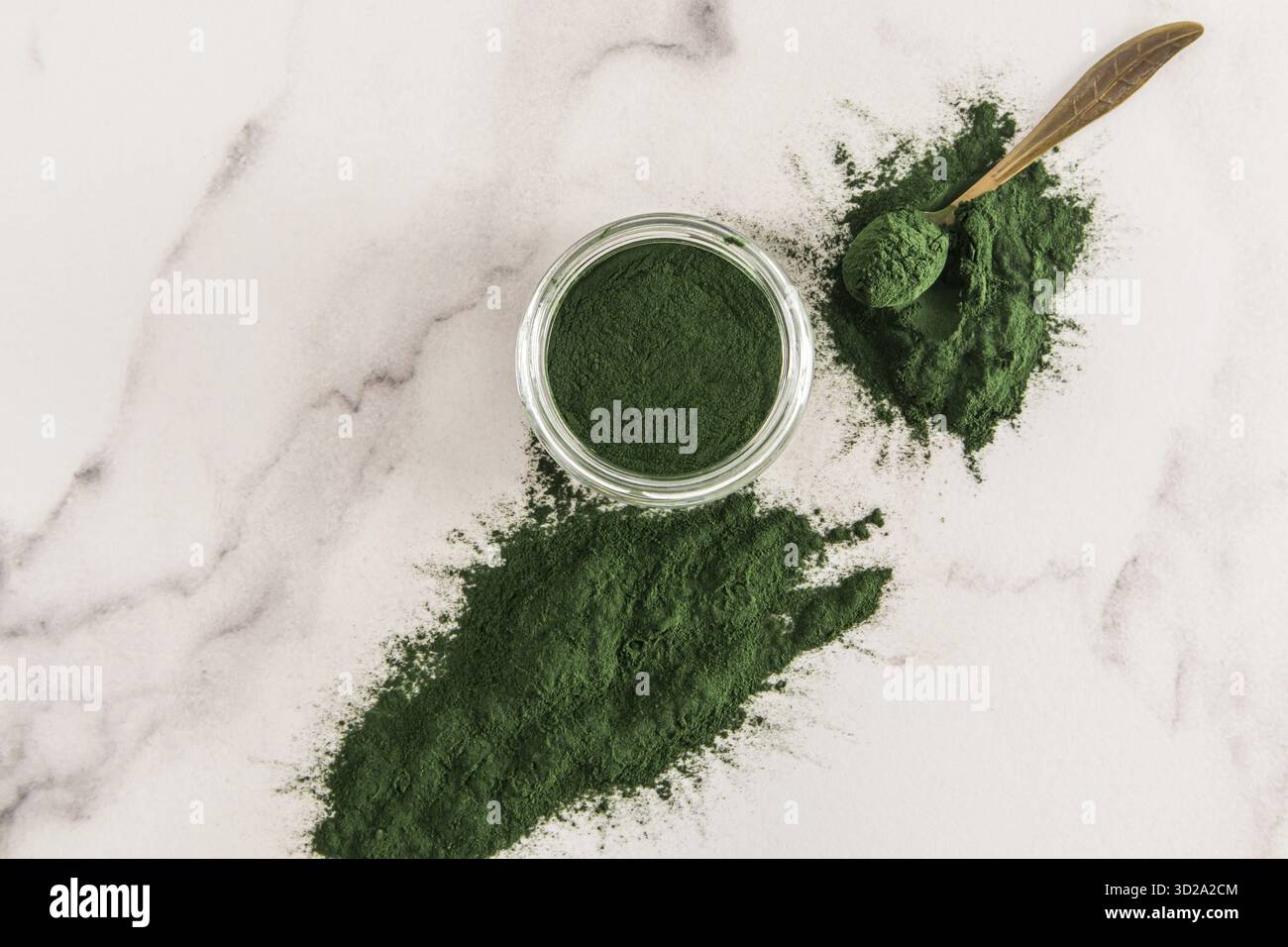 Un pot en verre rempli de poudre organique d'algues spiruline vertes sur un fond blanc marbre. vue de dessus. Détox Banque D'Images