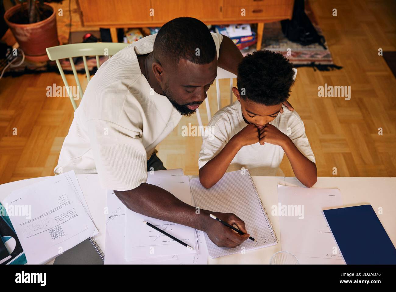 Vue en angle élevé du père enseignant son fils tout en résolvant un problème de mathématiques à la maison Banque D'Images