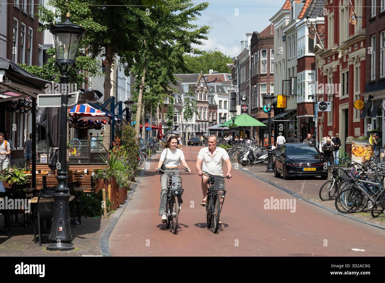 Deux cyclistes portant des chemises à manches courtes traversent une agréable rue commerçante au centre d'Utrecht. Banque D'Images