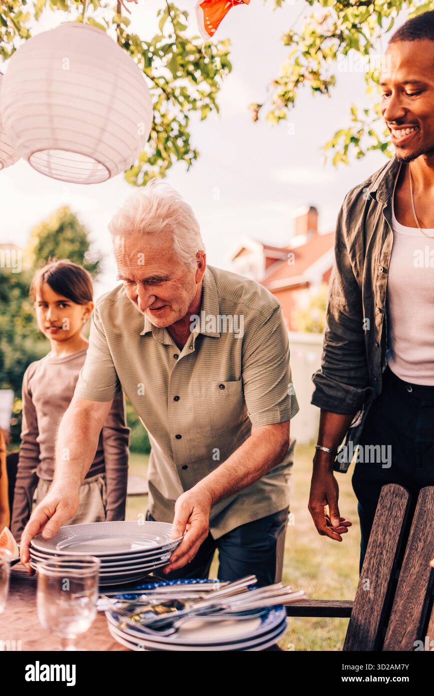 Homme senior dressant la table pour le dîner à la fête de réunion de famille Banque D'Images