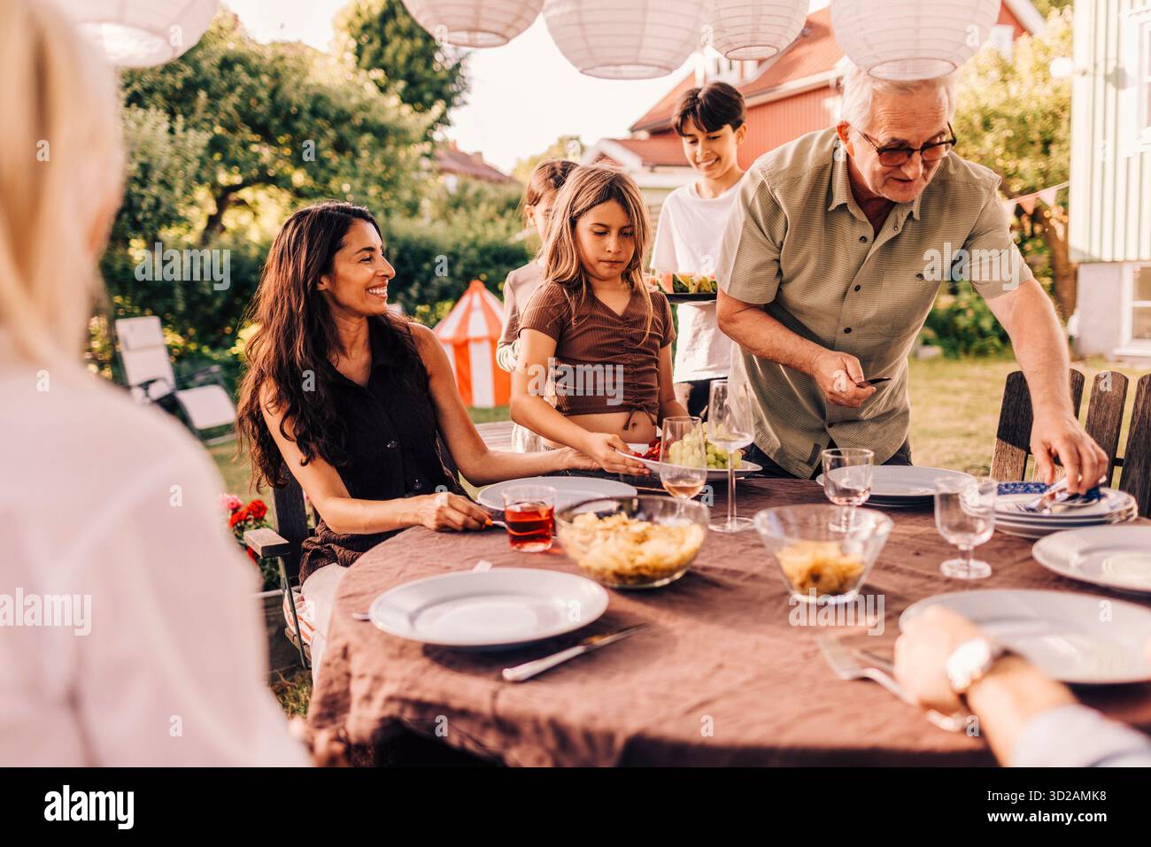 Petits-enfants aidant grand-père à mettre la table pour le dîner de réunion de famille Banque D'Images