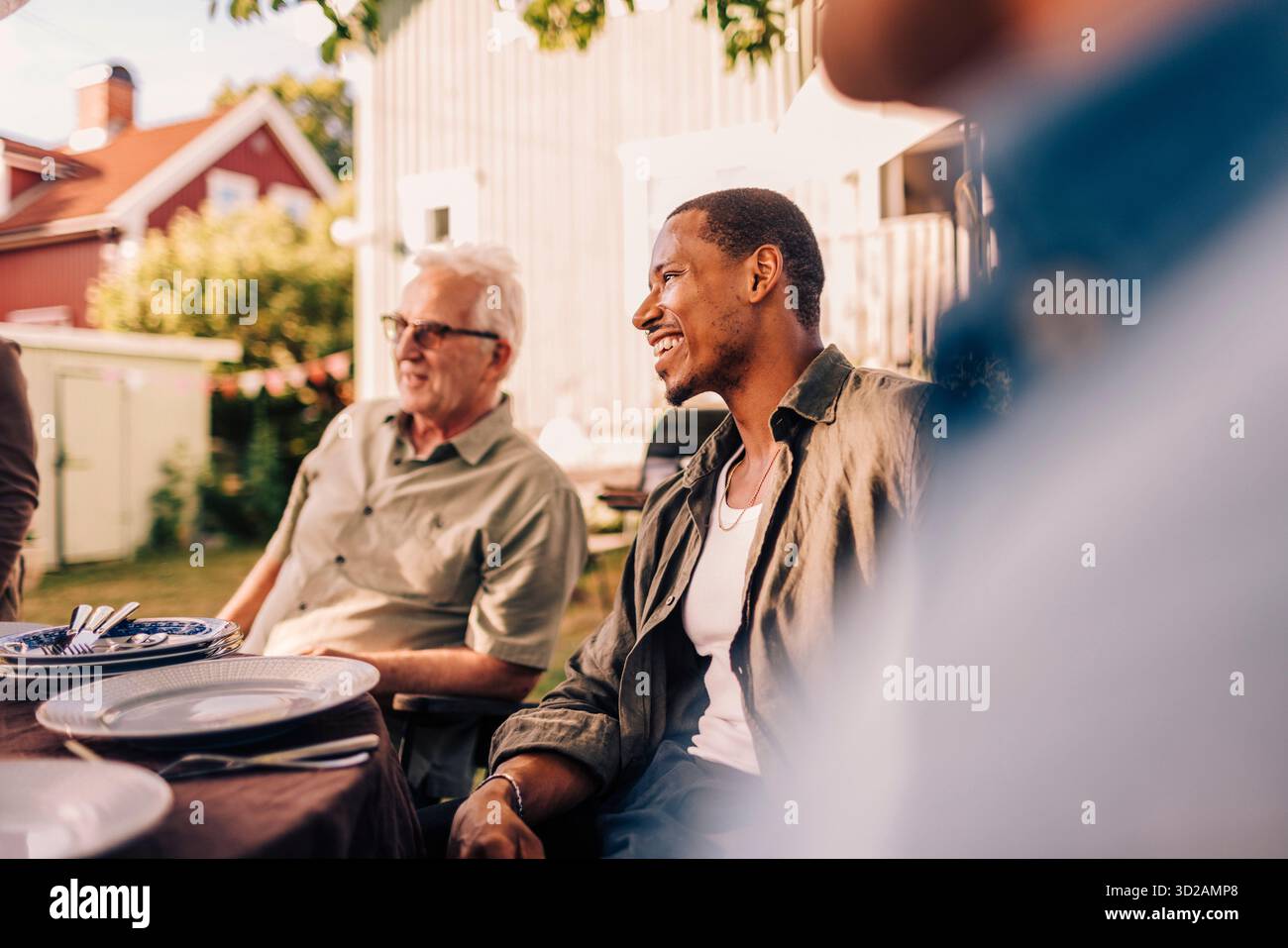 Homme heureux assis à la table à manger avec la famille dans la cour arrière Banque D'Images