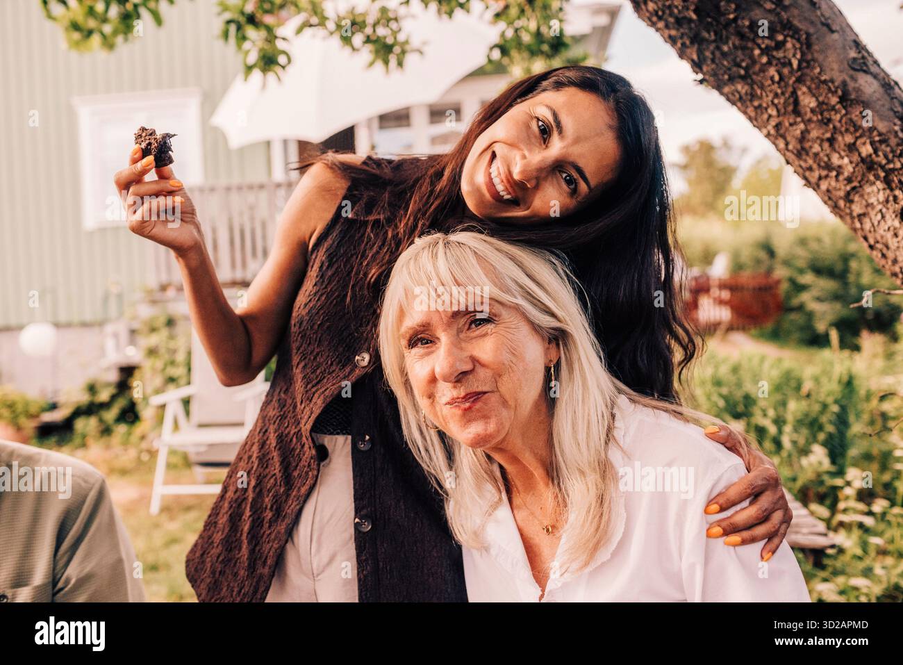 Portrait de femme souriante embrassant la mère à la fête d'anniversaire de cour arrière Banque D'Images