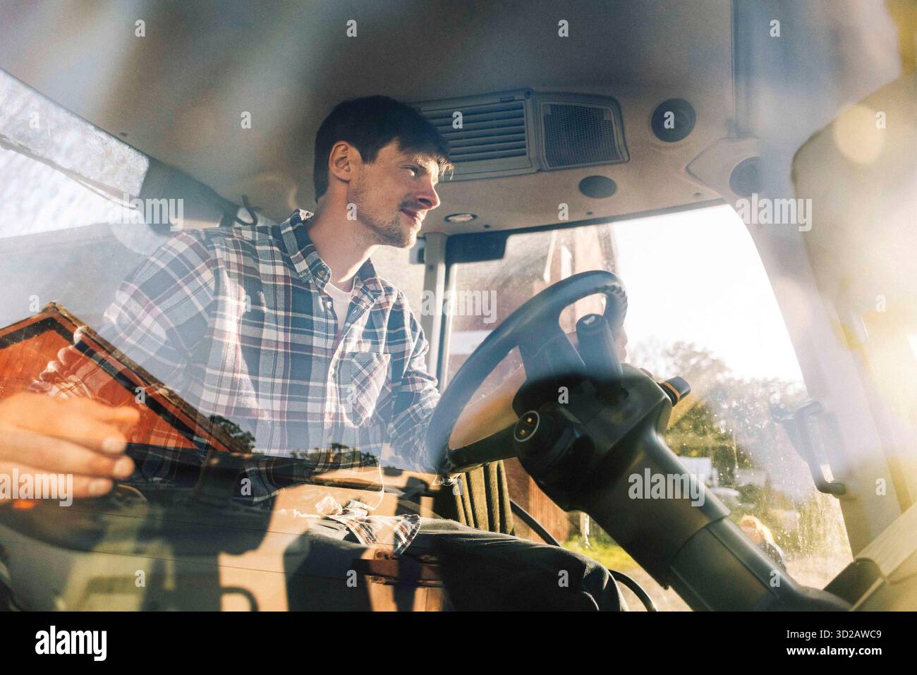 Agriculteur conduisant le tracteur tout en travaillant à la ferme Banque D'Images
