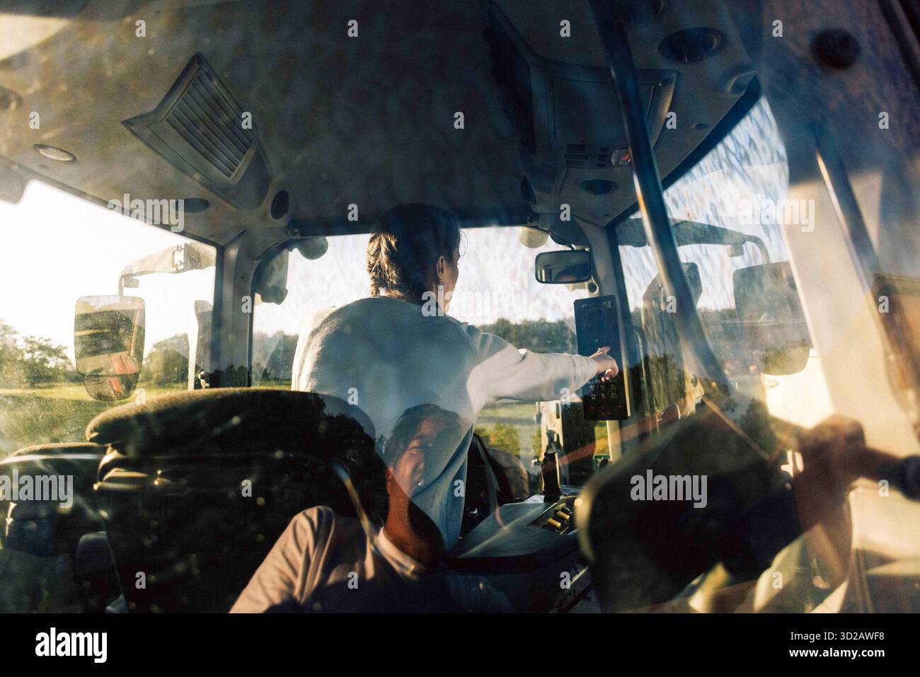 Vue arrière de l'agriculteur écran tactile de l'appareil pendant la conduite du tracteur dans la ferme Banque D'Images