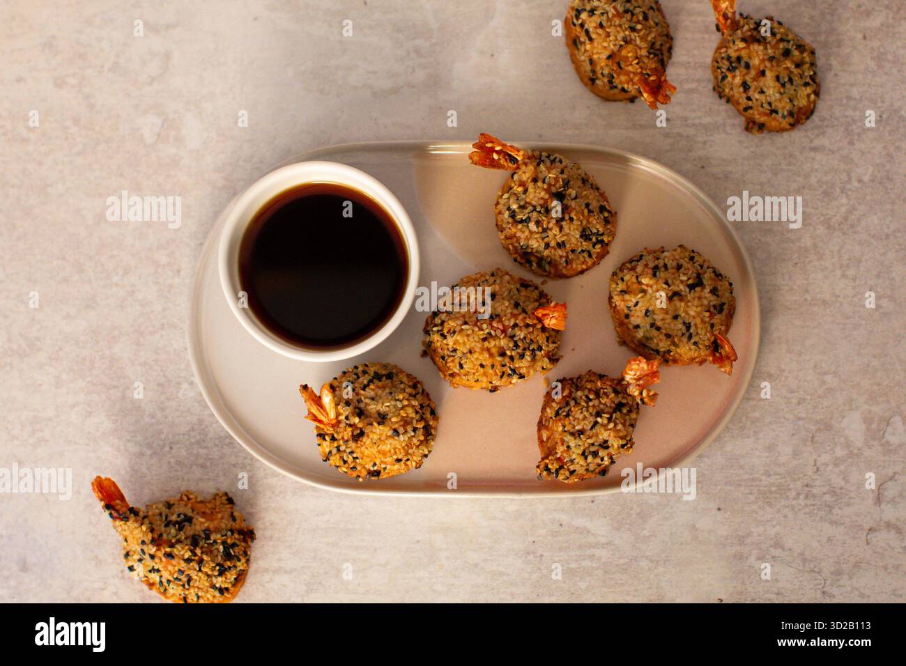 boulettes de crevettes croustillantes au sésame ou beignets de crevettes enrobés de graines de sésame noires et blanches, servies avec un bol de sauce soja foncée sur un p ovale en céramique Banque D'Images
