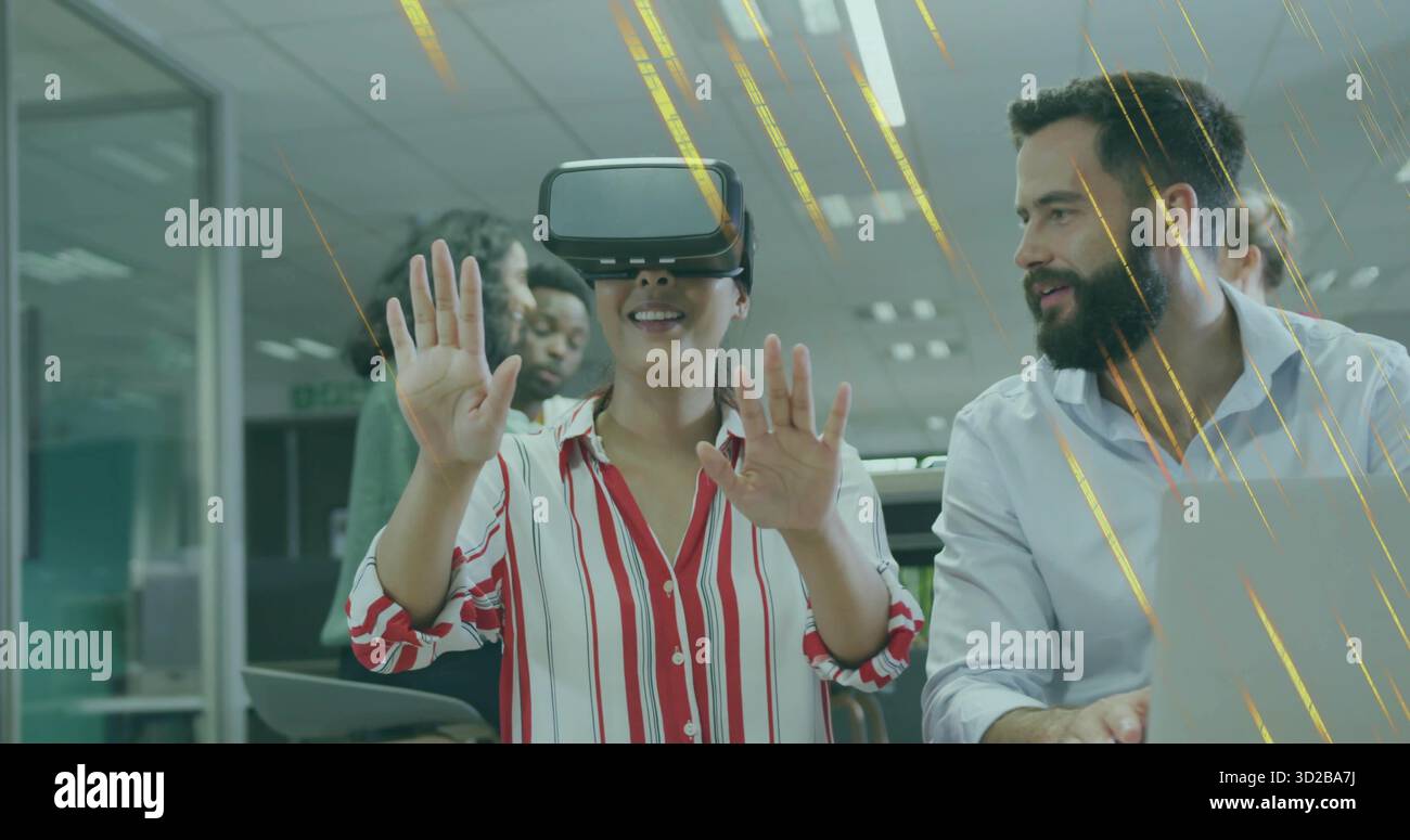 Femme portant un casque VR interagissant dans un bureau ouvert, avec des ordinateurs portables, des moniteurs et une tablette Banque D'Images