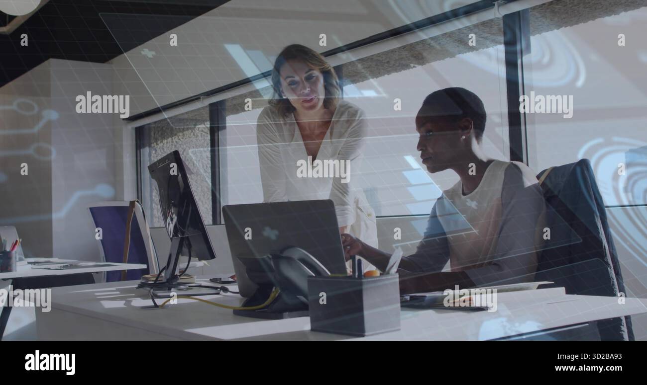 Collaboration de deux collègues femmes examinant l'écran d'un ordinateur portable au bureau de l'entreprise, avec des blocs-notes Banque D'Images