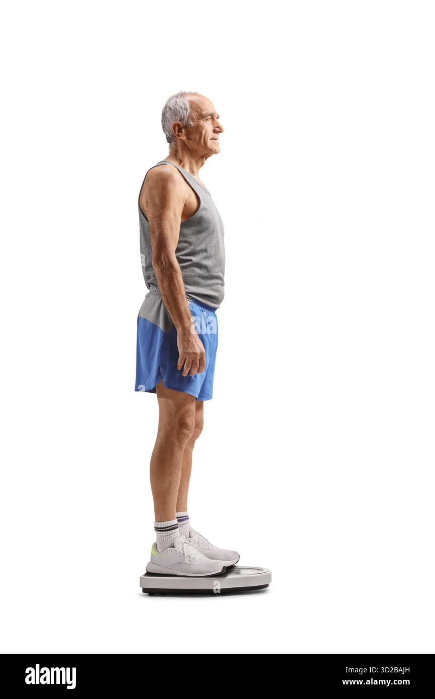 Plan de profil pleine longueur d'un homme mature en forme dans des vêtements de sport debout sur une échelle de poids isolé sur fond blanc Banque D'Images