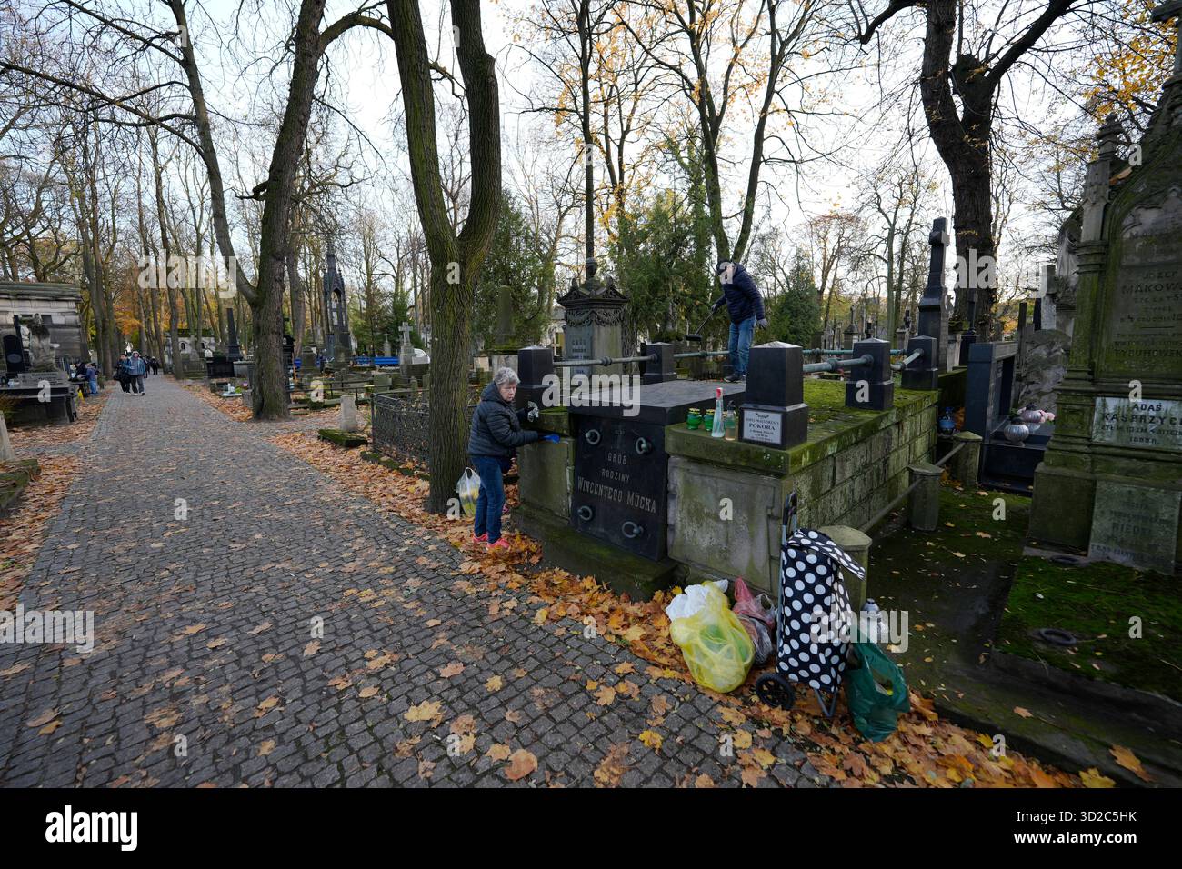 Un couple est vu en train de ranger une tombe familiale dans le cimetière de Powazki à Varsovie, en Pologne, le 31 octobre 2025. Banque D'Images