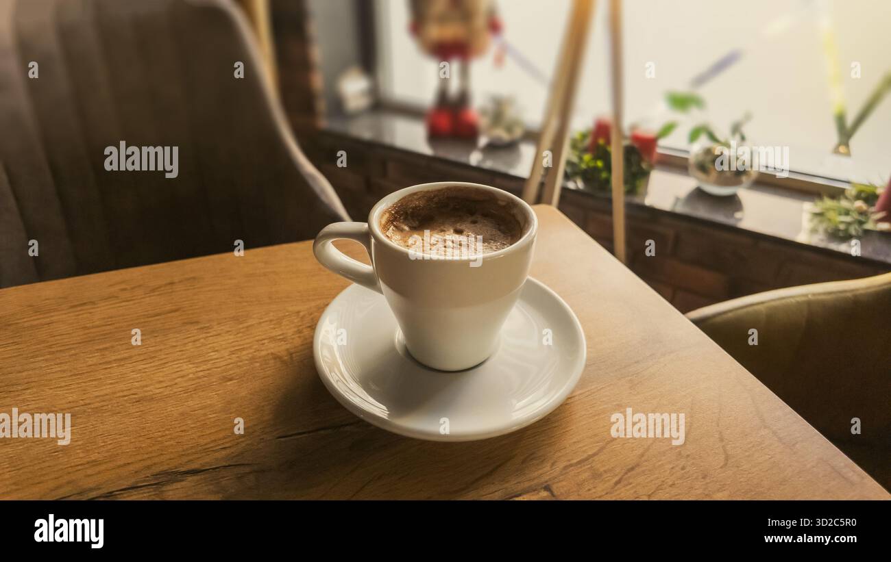 Tasse de café chaud sur une table en bois dans un café confortable, lumière chaude du matin créant une atmosphère paisible et une scène de style de vie accueillante Banque D'Images