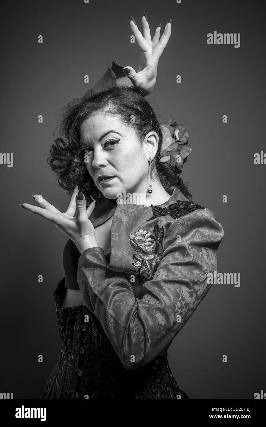 Danseuse de flamenco espagnol avec noeud dans les cheveux et le manteau rouge avec fond neutre. La danse traditionnelle en espagne Banque D'Images