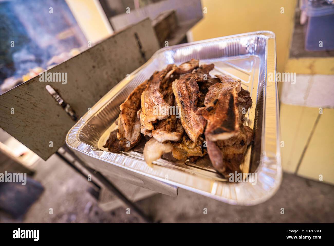 Morceaux de porc fraîchement grillés reposant dans un plateau en aluminium, juteux et fumé, prêts à servir lors de fêtes en plein air, buffets ou événements de restauration pour gat d'été Banque D'Images
