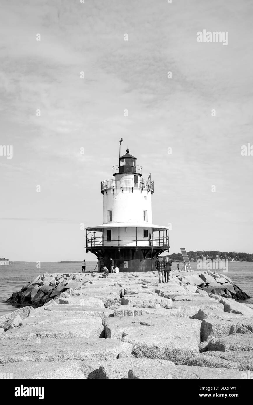 Photo en noir et blanc du phare historique de Spring point Ledge, debout le long de la jetée rocheuse avec les visiteurs par une journée côtière calme Banque D'Images
