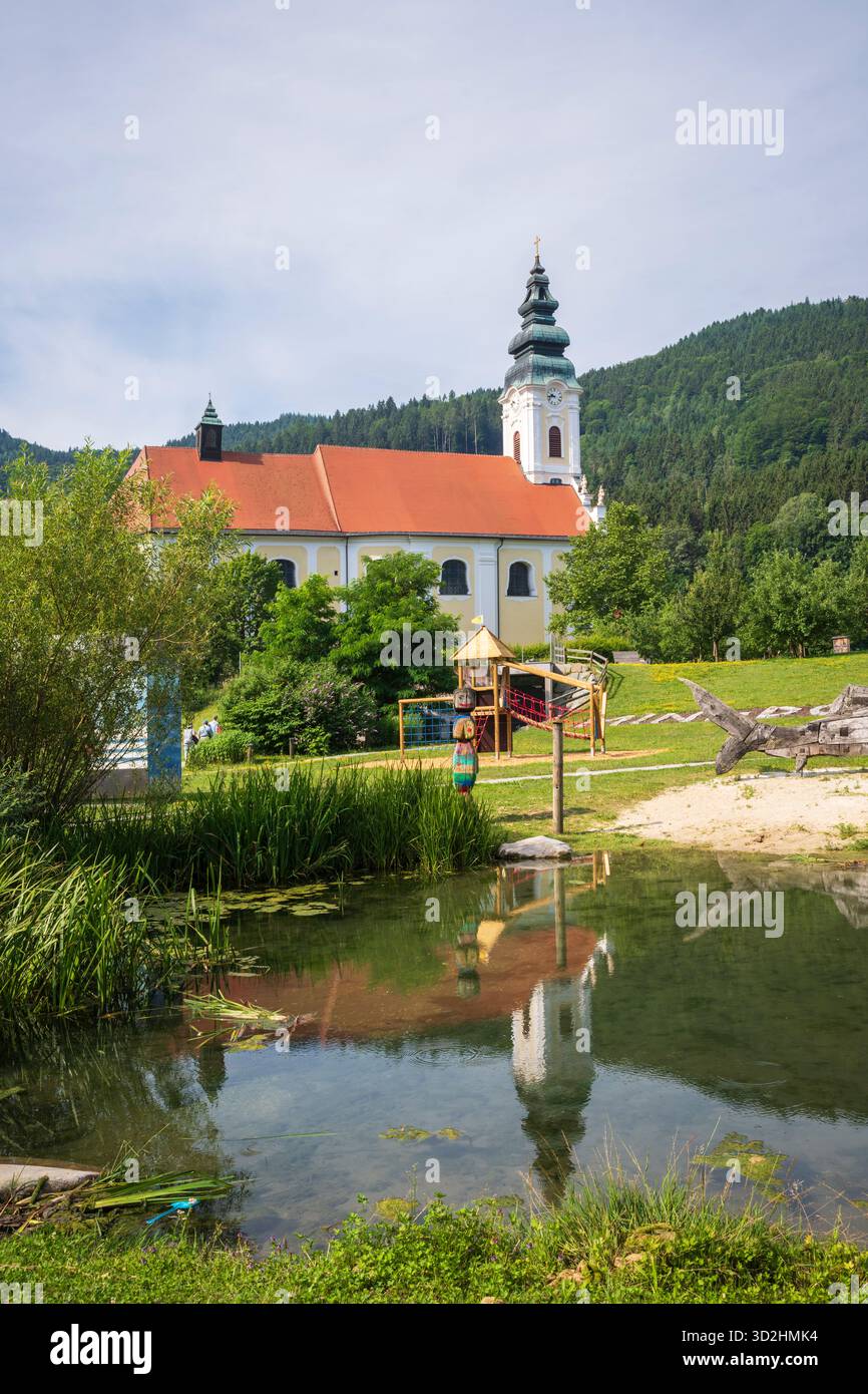 Engelhartszell, Autriche - 1er juillet 2019 : structure de jeu d'esturgeon béluga en bois et abbaye d'Engelszell reflétée dans l'étang. Banque D'Images