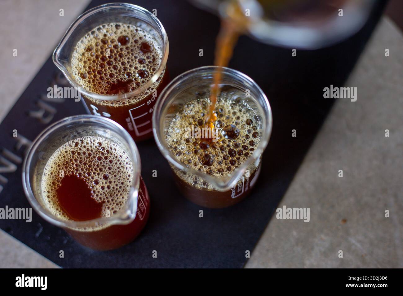 Focus sélectif café noir dans un verre transparent verser le café d'un pichet en verre dans un verre à mesurer transparent avec des chiffres indiquant la quantité sur t Banque D'Images