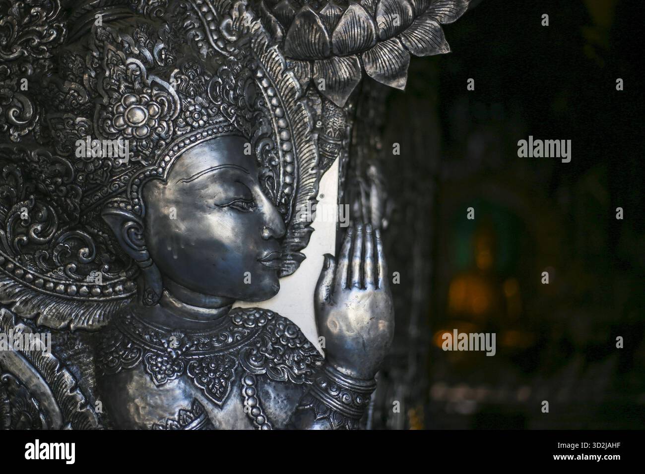 Sculpture sereine ornée d'argent métallique représentant une figure spirituelle. Art asiatique traditionnel détaillé, geste apaisant à la main, évoquant la paix et contemplant Banque D'Images
