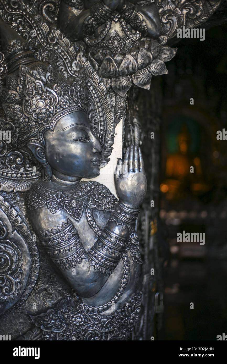 Sculpture argentée ornée d'une divinité asiatique avec des détails complexes se trouve dans le temple bouddhiste. figure spirituelle évoque un profond sentiment de paix et de ser Banque D'Images