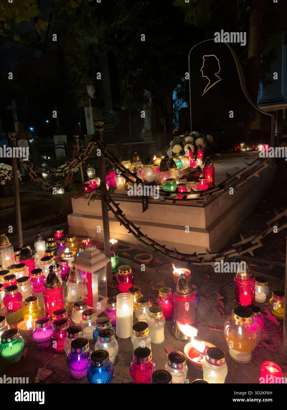 Le mémorial du jour de toutes les âmes rempli de bougies et de fleurs brillantes représente le souvenir, la foi et l'espoir. Atmosphère paisible de cimetière que les gens honorent - Image de stock capturée avec un smartphone
