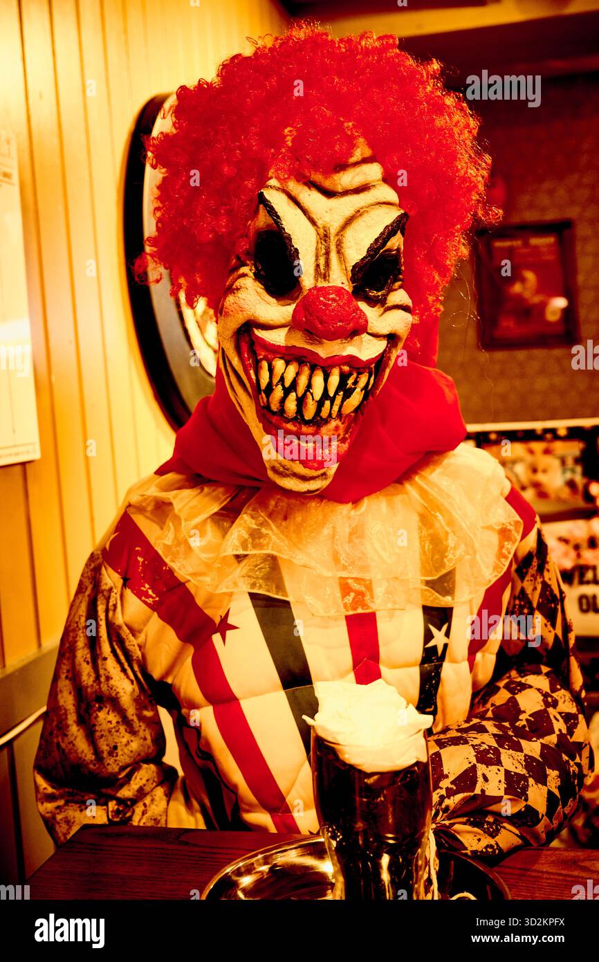 Sinistre clown d'horreur buvant stout à la table du pub Banque D'Images