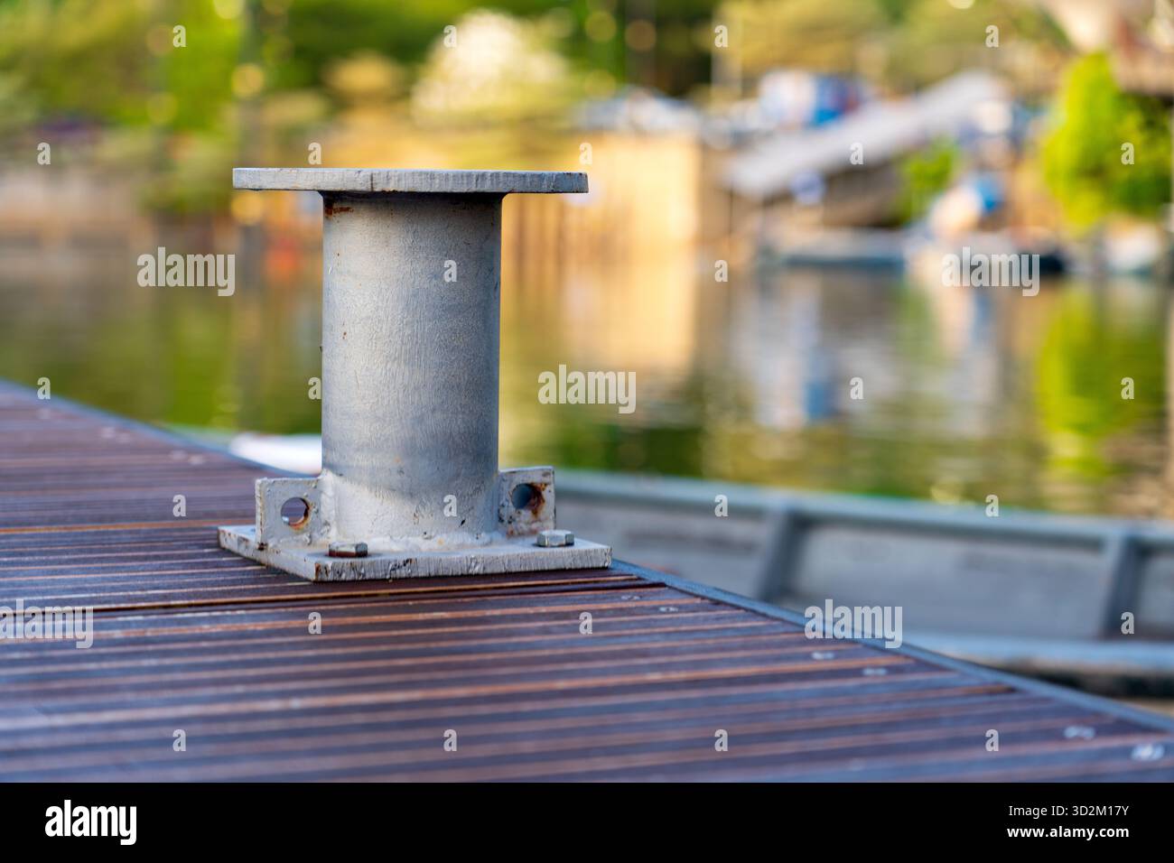 Borne en métal sur quai en bois avec corde fermement enveloppée, attachant un bateau dans un cadre de marina rustique avec fond doux Banque D'Images