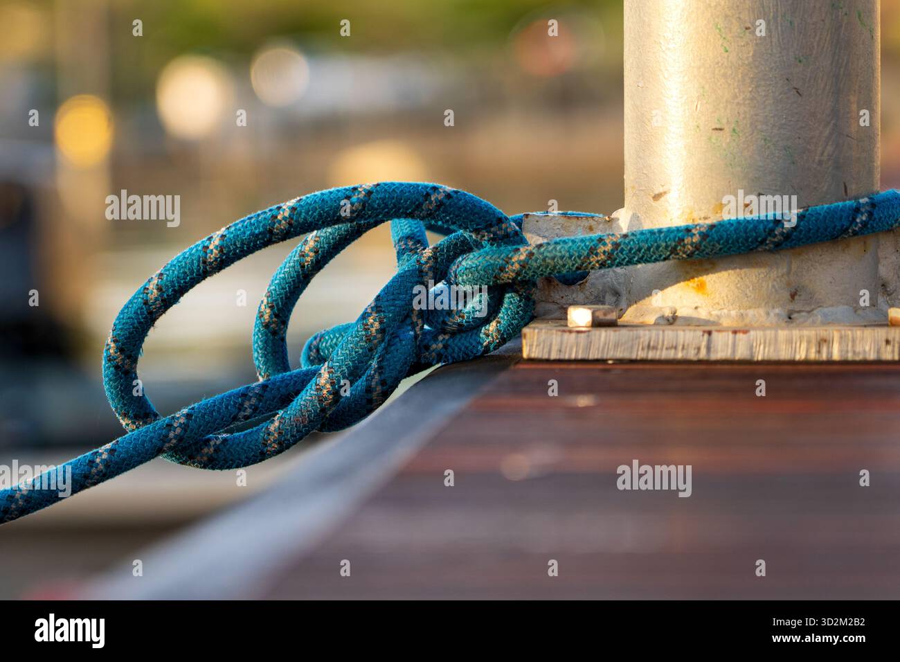 Solidement attaché Blue Rope enroulé autour de la borne en métal sur le quai en bois, nœud nautique tenant le bateau en place à Marina Banque D'Images