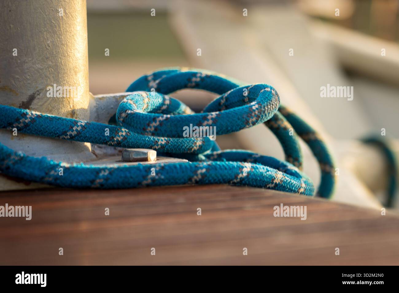 Solidement attaché Blue Rope enroulé autour de la borne en métal sur le quai en bois, nœud nautique tenant le bateau en place à Marina Banque D'Images