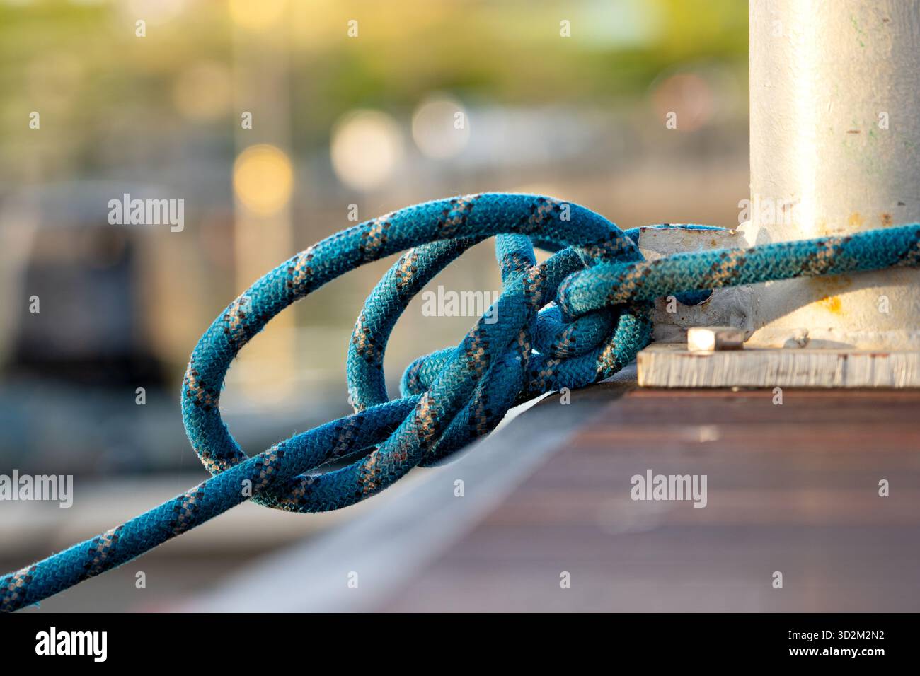 Solidement attaché Blue Rope enroulé autour de la borne en métal sur le quai en bois, nœud nautique tenant le bateau en place à Marina Banque D'Images
