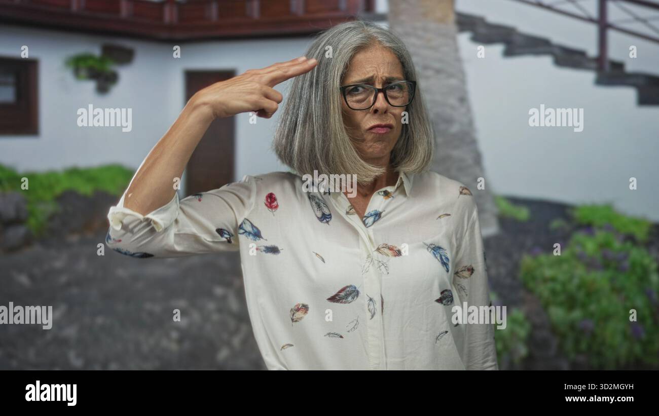 La femme pointe le doigt sur la porte d'entrée du bâtiment tout en grimaçant, main levée ; réglage de limite de gêne. Banque D'Images