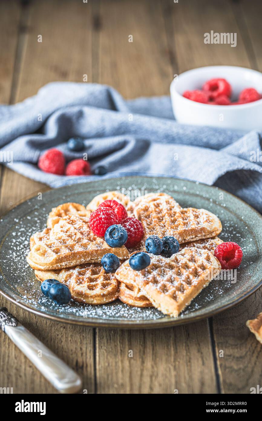 Gaufres maison avec sucre en poudre et baies sur une table en bois, verticale Banque D'Images