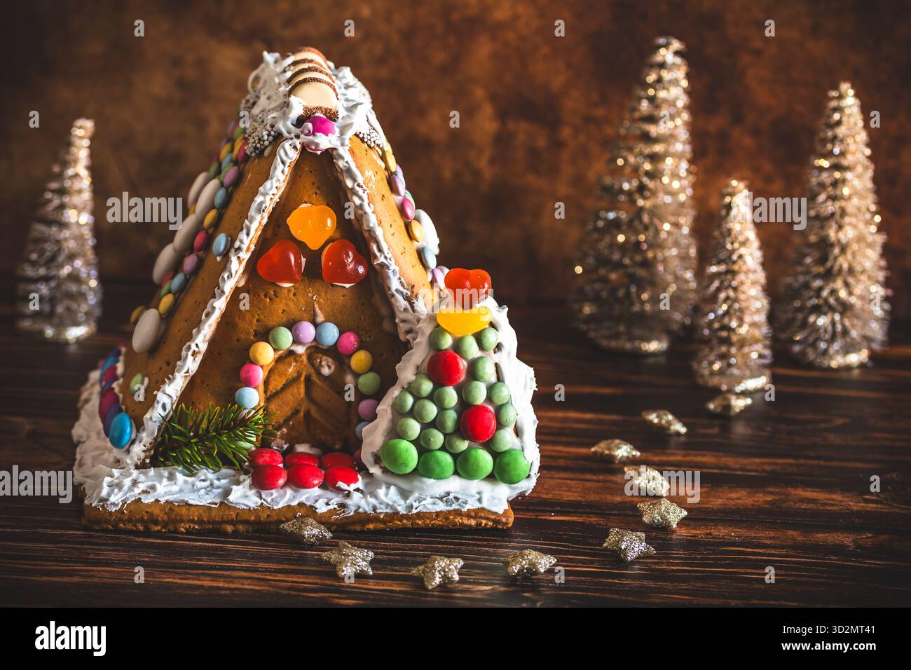 Maison en pain d'épices décorée de bonbons colorés et décoration de noël sur fond de bois. Banque D'Images