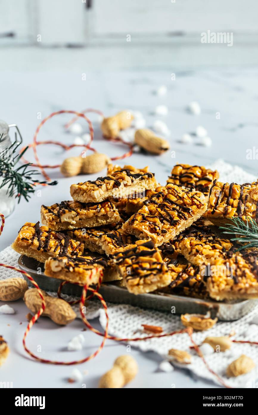 Biscuits faits maison au caramel aux arachides, biscuits de Noël au caramel salé et aux arachides, coupés en rectangles, fond blanc, vertical Banque D'Images