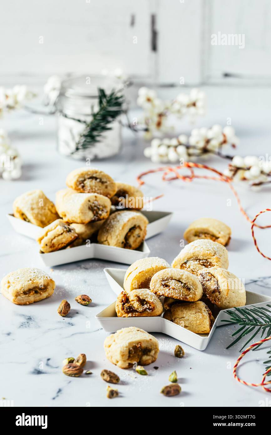 Biscuits de pâte brisée avec remplissage à la pistache, cuisson de Noël, rouleaux de pistache sur fond blanc, vertical Banque D'Images