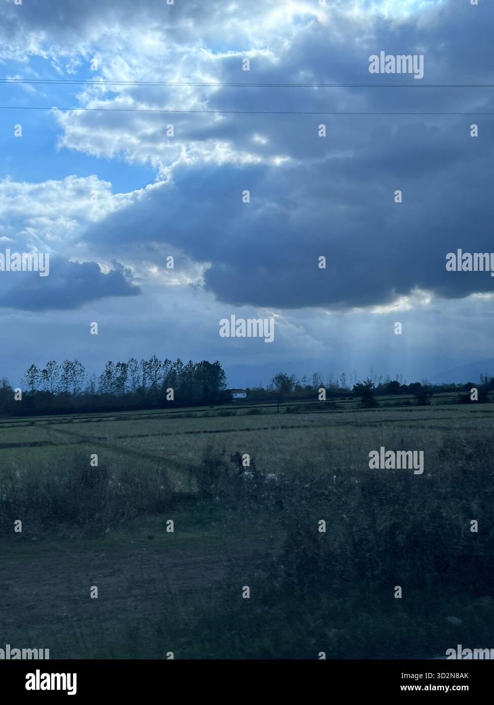 Les rayons du soleil perdent les nuages orageux au-dessus des rizières de Gilan et des contreforts lointains d'Alborz - un moment serein dans la campagne caspienne. Banque D'Images