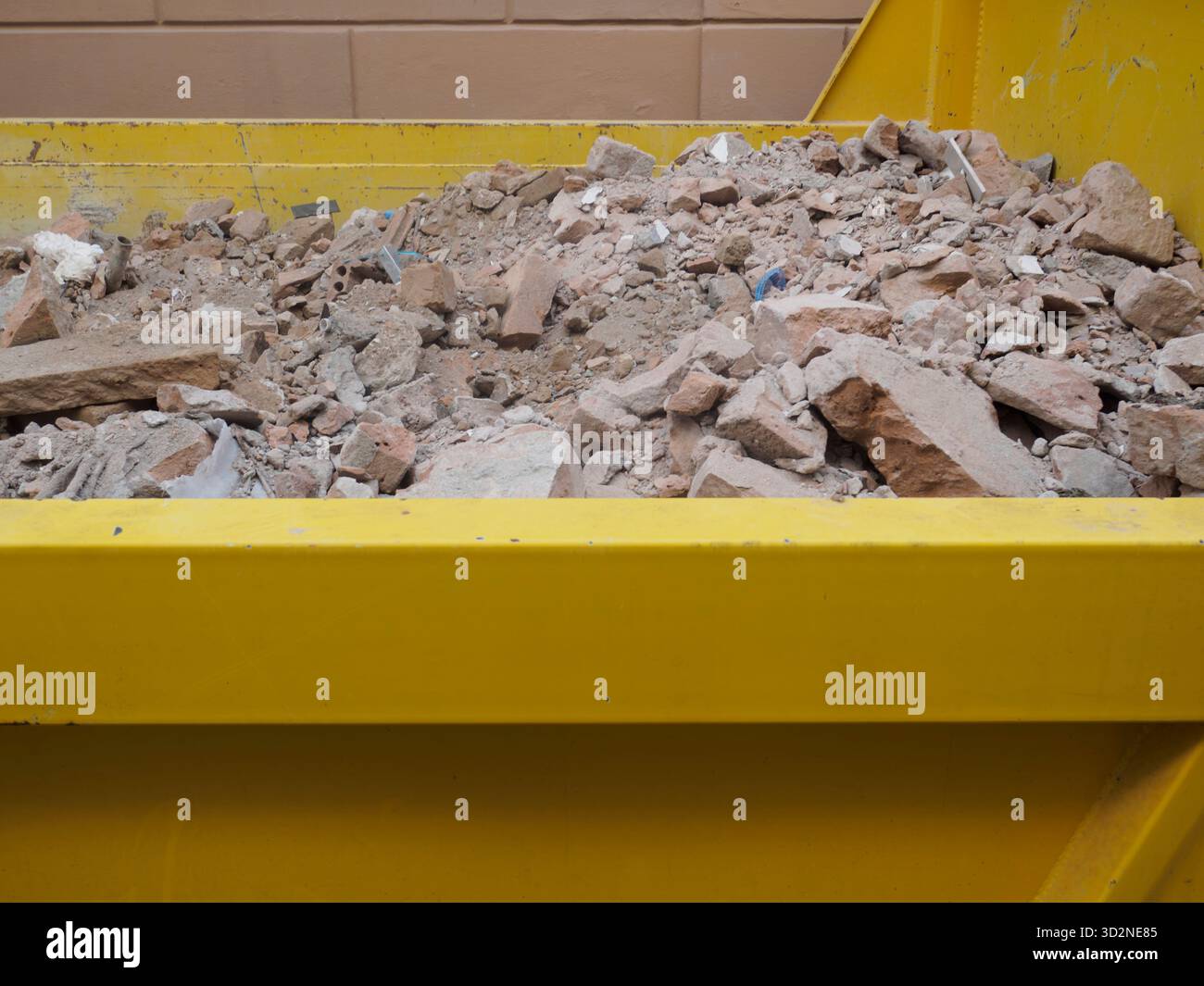 Cremona, Italie 14 août 2025 conteneur à ordures jaune industriel débordant de déchets de construction, de débris et de béton, illustrant les concepts Banque D'Images