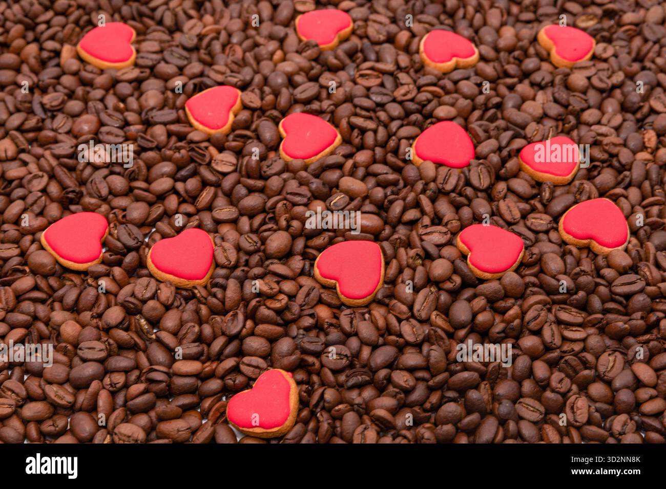 Biscuits coeur rouge sur fond de grains de café torréfiés pour le thème de l'amour Banque D'Images