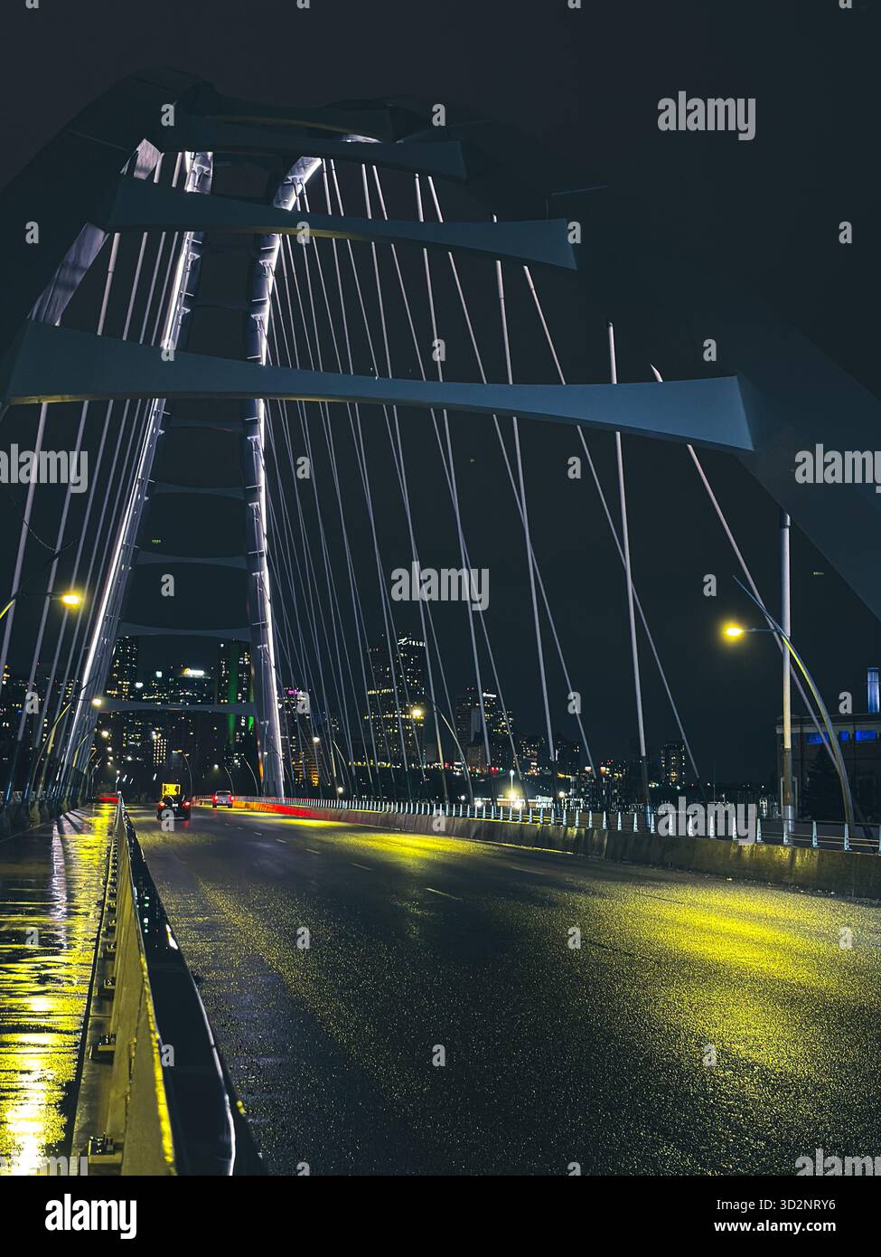 Composition nocturne symétrique du pont Walterdale à Edmonton, Alberta, Canada, qui brille sous les lampadaires après les précipitations Banque D'Images