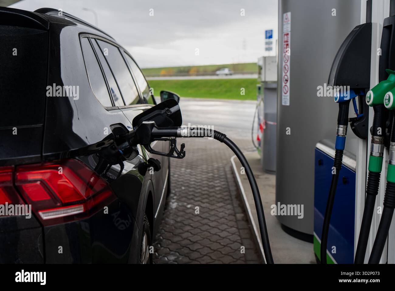 Ravitaillement de voiture noire à la station-service moderne avec buse de carburant insérée dans le réservoir illustrant l'approvisionnement en énergie de transport, la préparation de voyage et l'autom Banque D'Images