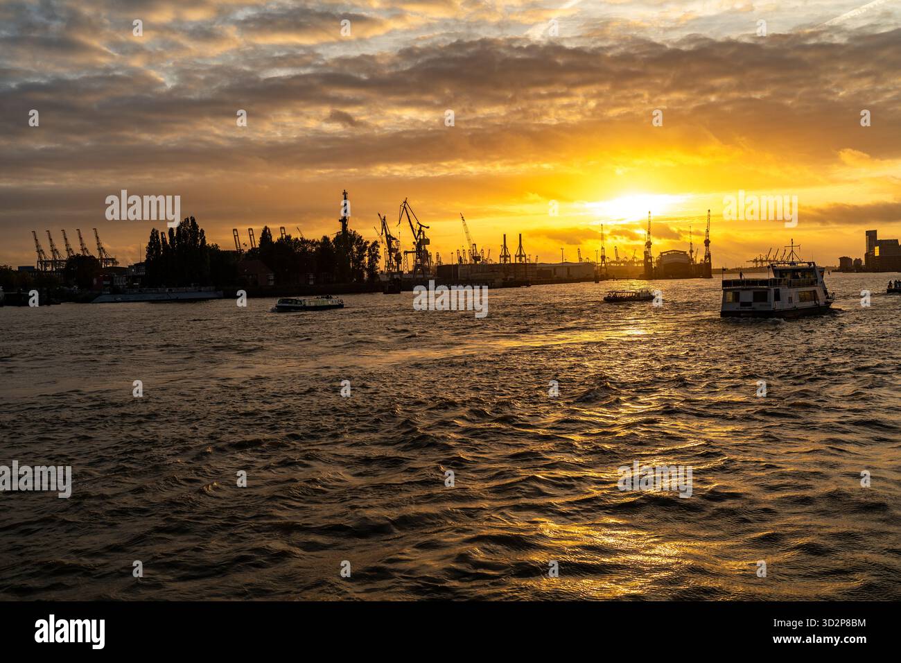 Grues portuaires de Hambourg et bateaux au coucher du soleil sur l'Elbe Banque D'Images