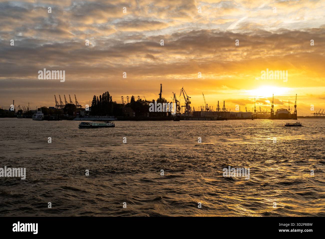 Grues portuaires de Hambourg et bateaux au coucher du soleil sur l'Elbe Banque D'Images