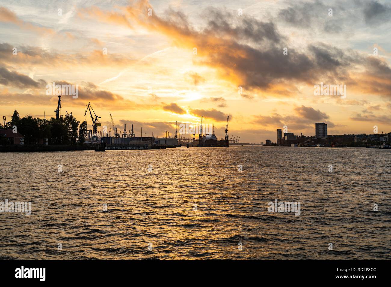 Grues portuaires de Hambourg et bateaux au coucher du soleil sur l'Elbe Banque D'Images