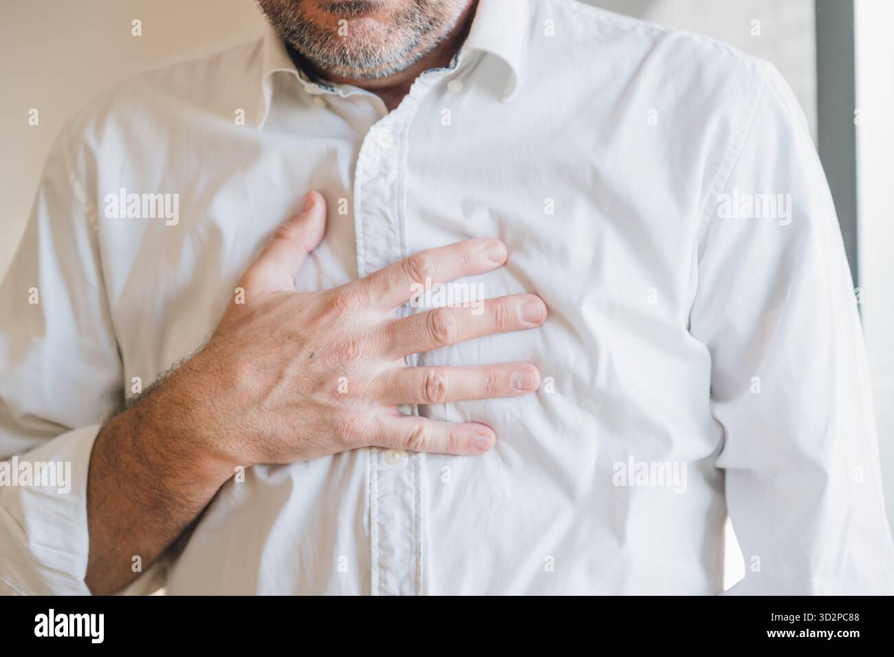 Homme d'affaires en chemise blanche souffrant de douleurs thoraciques sévères, gros plan de l'homme serrant sa poitrine en raison de douleurs cardiaques soudaines, concept de santé d'urgence. S Banque D'Images