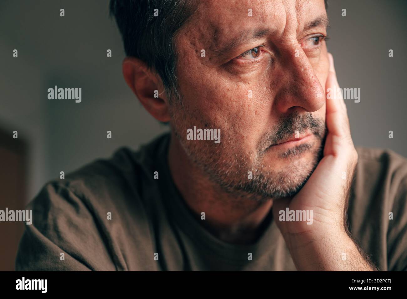 Homme adulte agité assis en silence, penché sur la main, montrant l'expression faciale fatiguée et mal à l'aise dans le portrait en gros plan, concept de procrastination. Séléc Banque D'Images