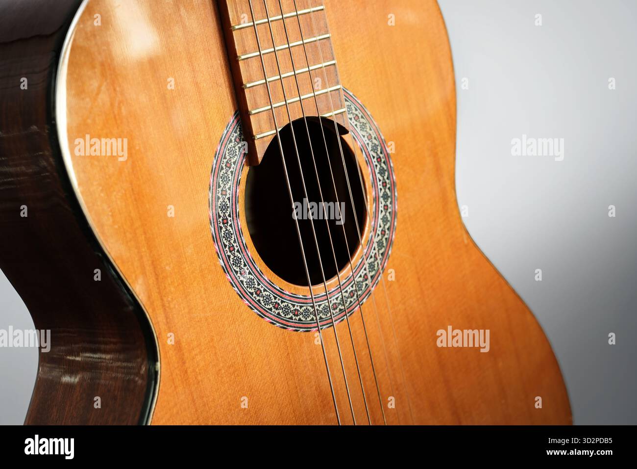 Trou sonore et cordes d'une guitare acoustique en bois rougeâtre, partie d'un instrument de musique, fond gris, foyer sélectionné, profondeur étroite de fiel Banque D'Images