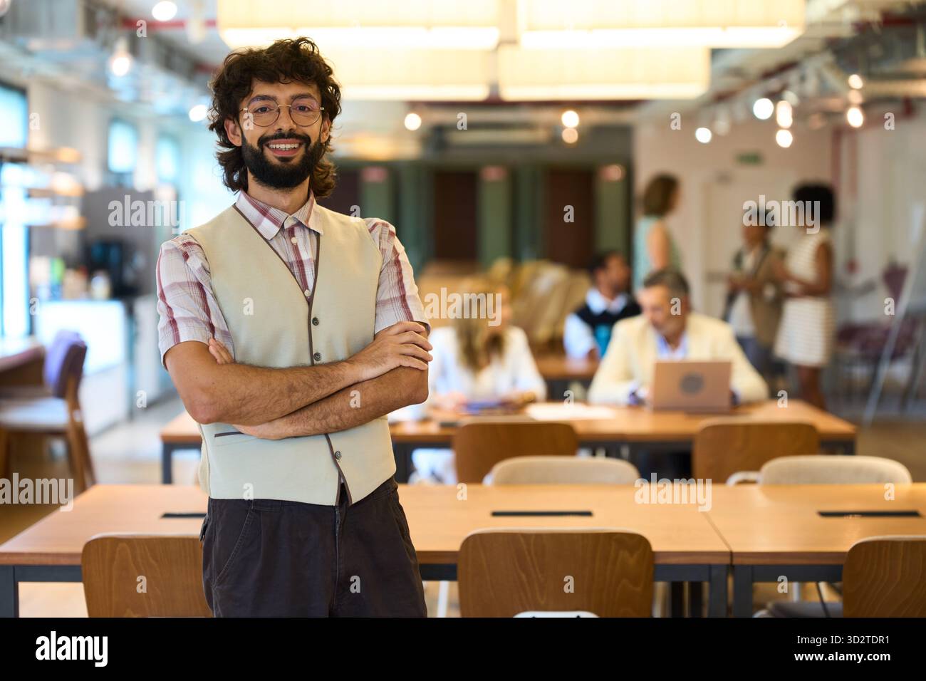 Homme professionnel souriant, bras croisés au bureau Banque D'Images