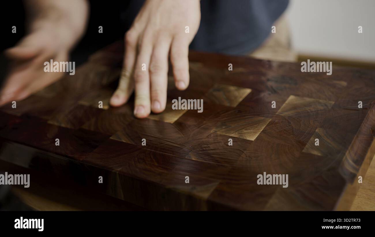 La main repose sur une planche à découper à motifs avec texture de grain fin polie Banque D'Images