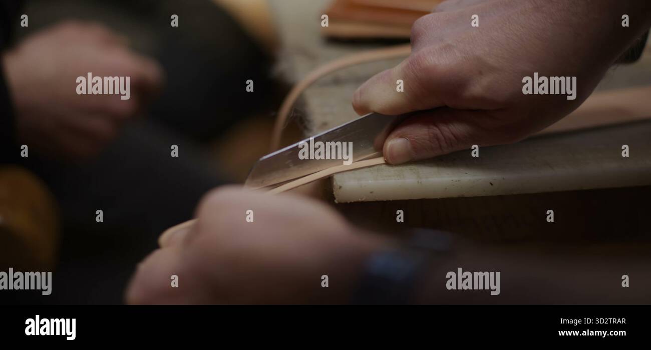 Coupe précise du cuir avec couteau guidé par une pression ferme de la main Banque D'Images
