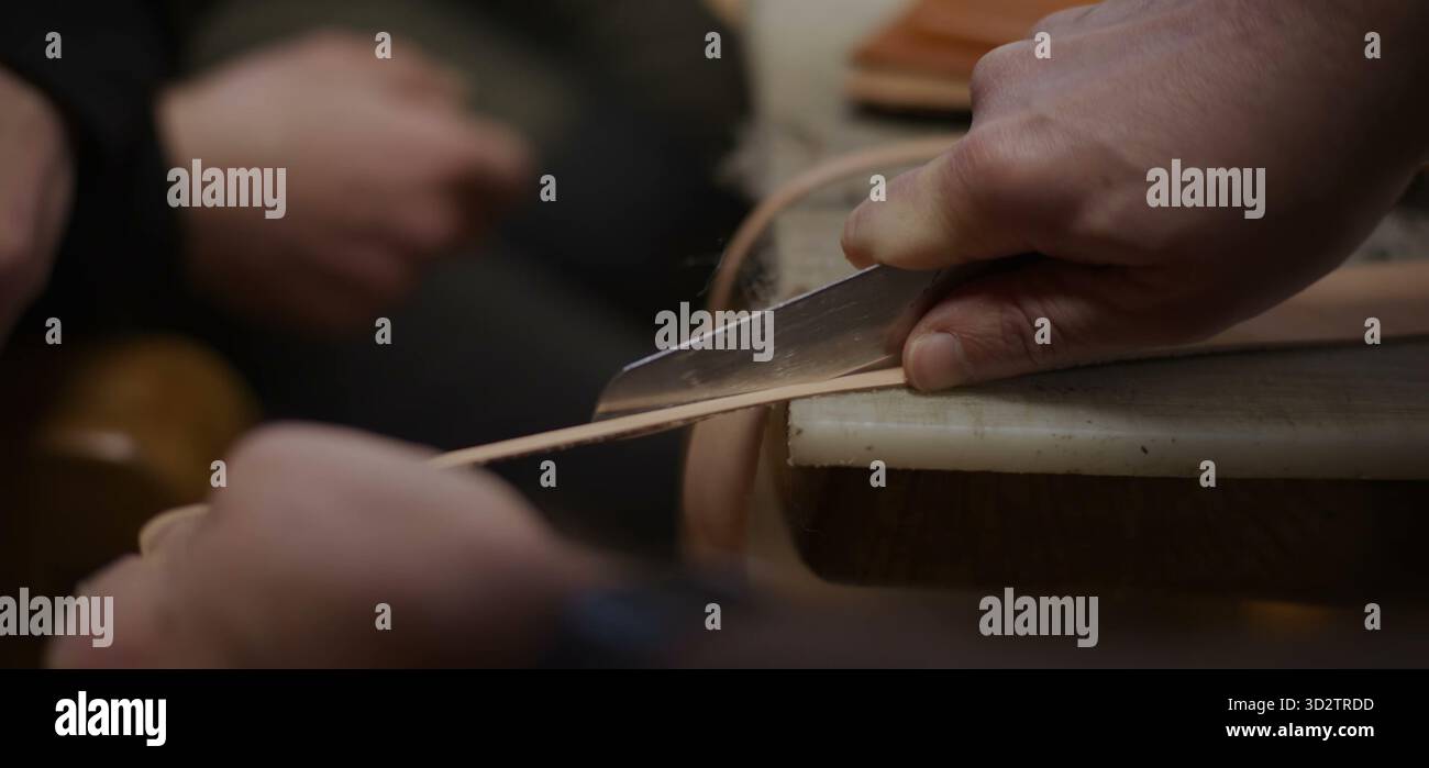 Coupe précise du cuir avec couteau guidé par une pression ferme de la main Banque D'Images